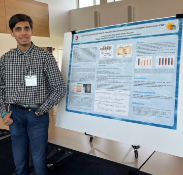 Student stands with presentation poster board
