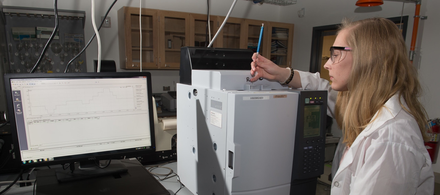 Student wearing lab coat conducts experiment